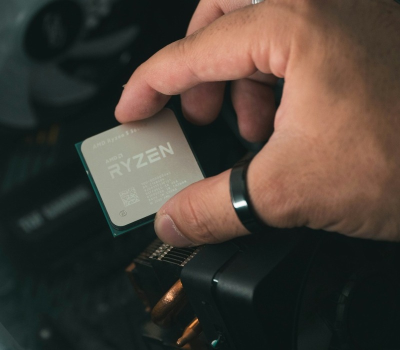 Close up of a person holding an AMD Ryzen 5600X CPU near a PC case