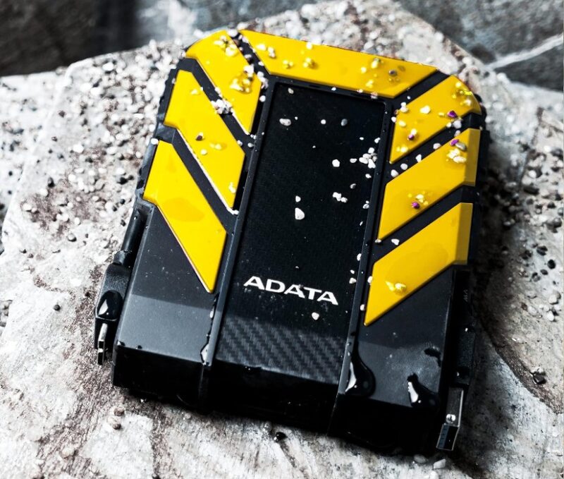 Adata HD710 Pro 2TB Yellow and black external hard drive on a white surface in the outdoors