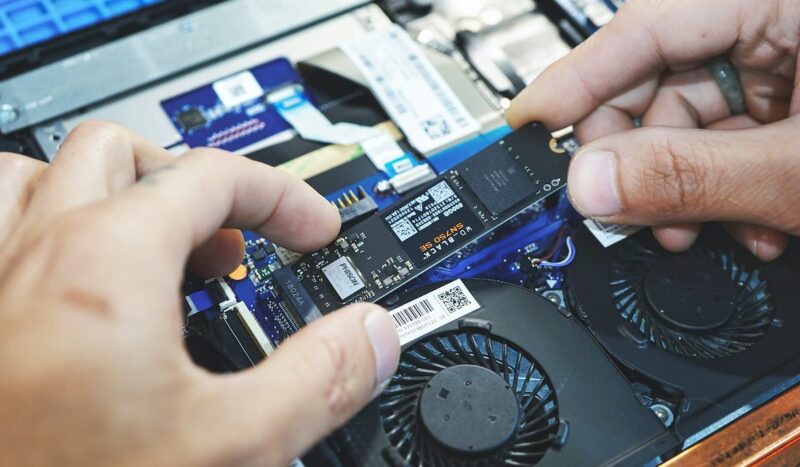 Closeup of two hands installing NVMe SSD in a laptop