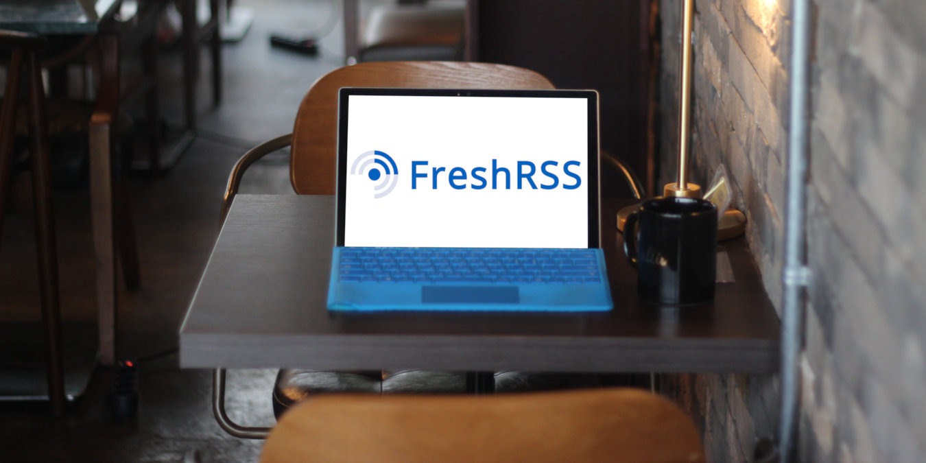 A photograph of a laptop on a table inside a cafe.