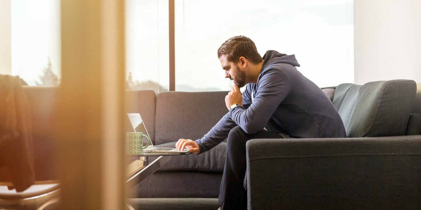 Man Sitting On Couch And Using A Computer