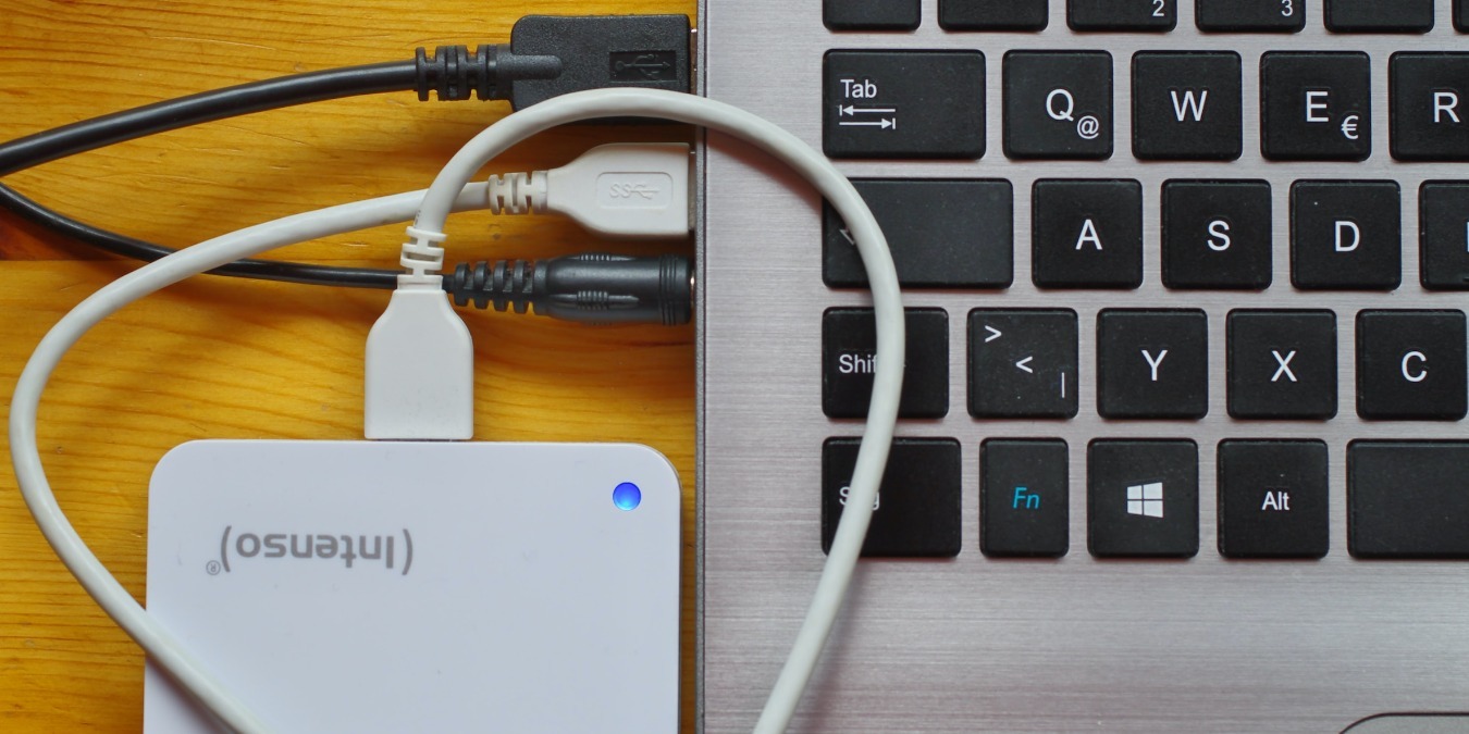 USB hard drive connected to a laptop on a brown desk