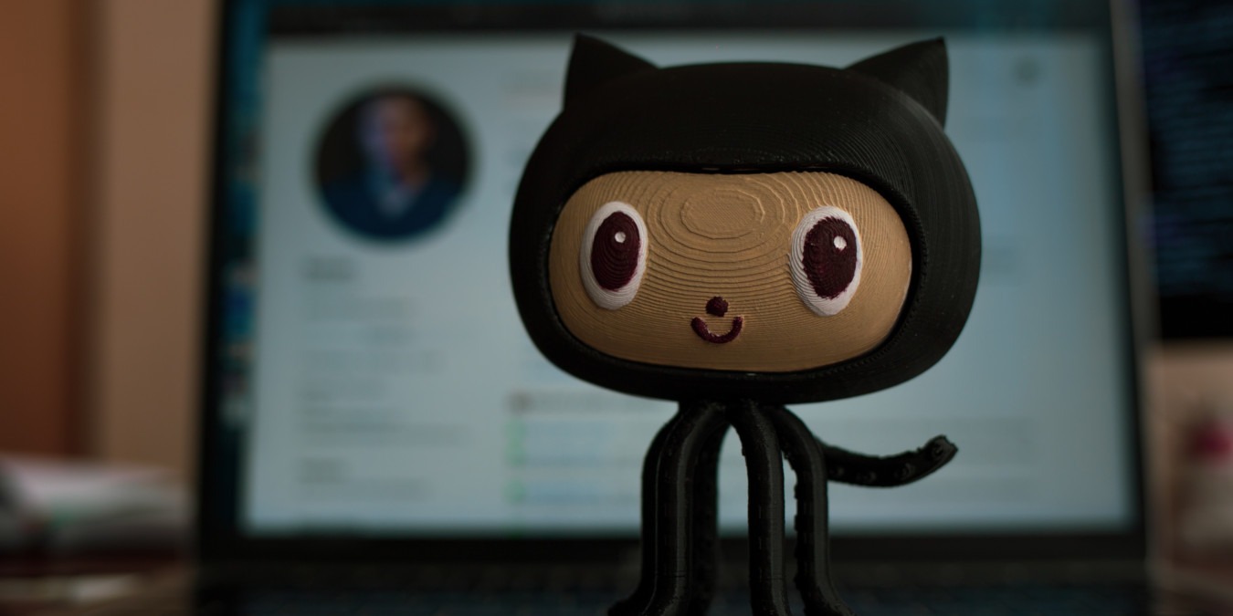 A photograph of the Github mascot in front of the Github webpage.
